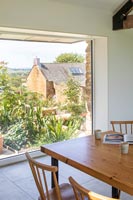 Wooden dining table with view to garden through large windows 