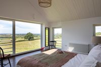 Modern bedroom with large windows and panoramic views of the countryside 