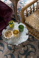 Wicker chair with leopard print cushion and decorative glassware on table 