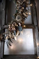 Dark coloured wreath of dried flowers and feathers with fairy lights 
