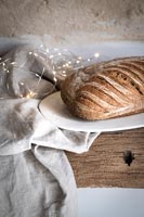 Loaf of bread and fairy lights on rustic table 