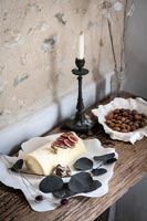 Goats cheese, figs and nuts on rustic table next to textured wall 