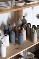 Collection of ceramic bottles in muted tones on shelf 