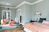Pink seating on colourful rug in green painted bedroom 