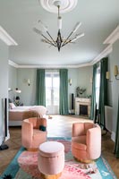 Pink seating area on colourful rug in large green painted bedroom 