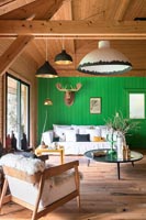 Modern country living room with bright green painted wooden feature wall 
