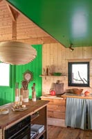 Wooden country kitchen with green painted ceiling and feature wall 