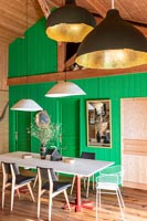 Modern dining room with green painted wooden feature wall 