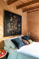 Black artwork on wooden bedroom wall 