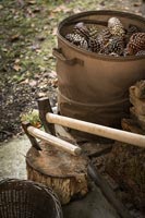 Axes in log next to basket of collected pinecones 