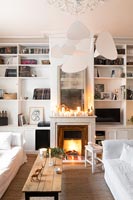 Lit fireplace and candles in white living room at Christmas 