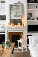 Display of lit candles on mantelpiece of white living room at Christmas