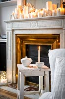 Display of lit candles on white marble mantelpiece at Christmas 