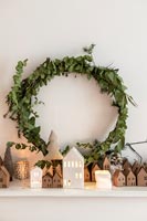 Wreath of foliage on mantelpiece with display of tiny houses 