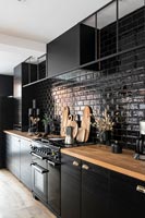 Modern black kitchen with wooden floor and worktops 