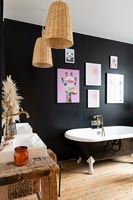 Roll top bath in modern bathroom with black painted feature wall 