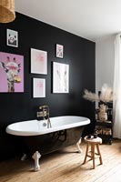 Black painted feature wall in modern bathroom with roll top bath