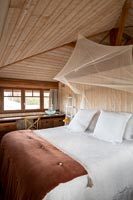Country bedroom with mosquito net canopy over bed 
