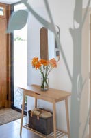 Flowers on small wooden modern console table in hallway 