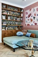 Modern living room with William Morris wallpaper behind shelving unit 