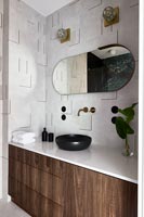 Modern bathroom with textured tiling on wall and wooden cabinet