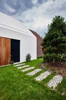Stone path in lawn leading to modern house exterior 