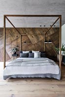 Modern bedroom with wooden wall and fourposter bed 
