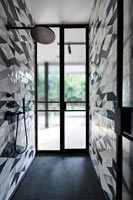 Modern wet room with patterned tiling on wall 