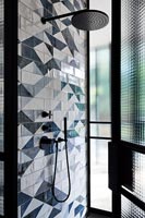 Shower with patterned tiling on wall 