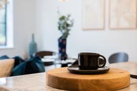 Black cup and saucer on round wooden chopping board 
