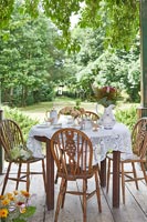 Afternoon tea on wooden terrace overlooking country garden 