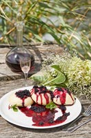 Wine and cakes with forest fruits on garden table 