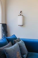 Hanging wall light next to modern blue sofa 