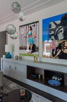 Colourful paintings above sideboard in modern living room 