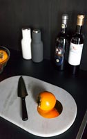Orange Sharon fruit on white marble chopping board in black kitchen 