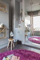 Pink and grey bedroom with tiny alcove sink next to mirrored wardrobe 