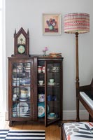 Classic dark wood display cabinet next to standard lamp 