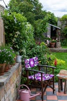Garden chair with purple patterned fabric and pink watering can 