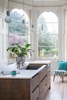 Large kitchen island with sink and view through bay windows 