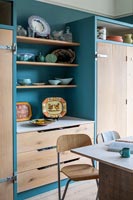 Plates and bowls displayed on shelves in modern wooden kitchen 