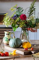 Detail of flower arrangement on country table with harvested vegetables 
