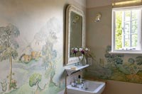 Fresco of country scenes on bathroom wall around sink 