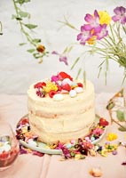 Cake on garden table covered in flowers for celebration picnic 