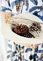 Collected pinecones and dried flowers in straw hat 