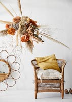 Dried flowers and grasses arrangement next to wicker chair 