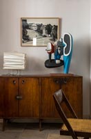 Modern sculpture on old wooden sideboard in dining room 