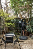 Large statue in small courtyard garden with cafe style table and chairs 