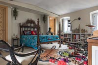 Carved wooden bed in eclectic bedroom - floor covered in shoes 