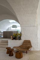 Sisal seat and wooden foot stools against white stone walls 