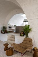 Sisal seat and wooden foot stools against white stone walls 